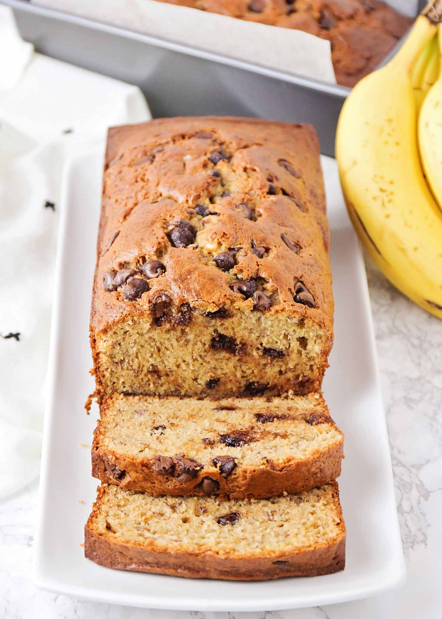 A partially sliced banana bread loaf on a white plate.