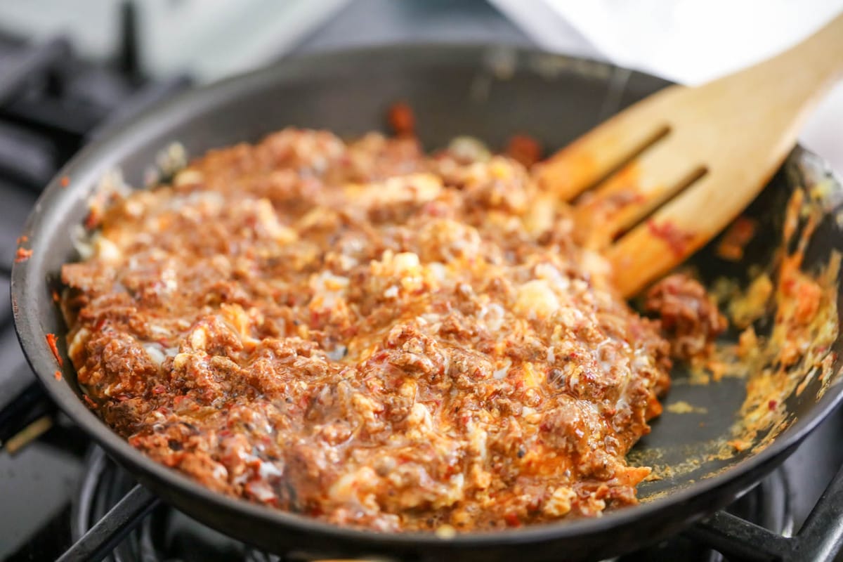 Cooking chorizo and cheese in a pan on the stove.