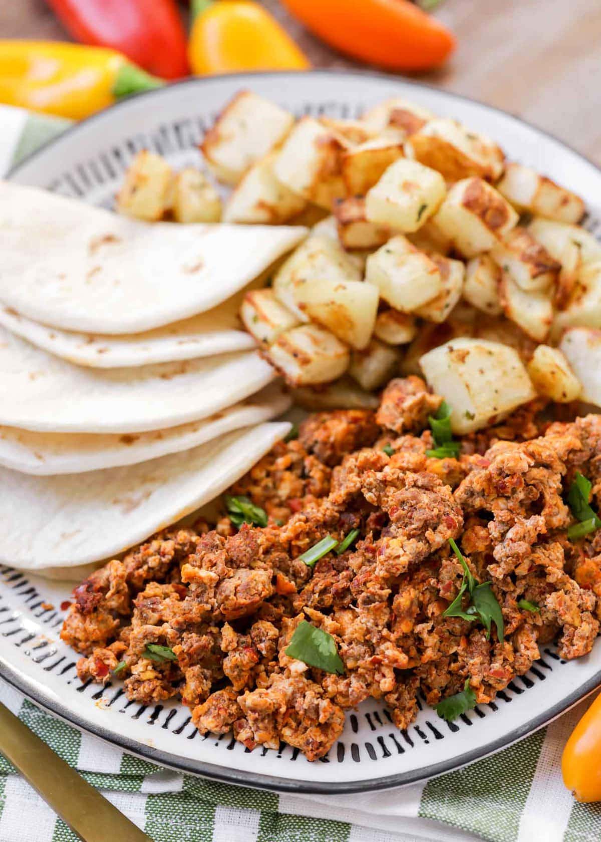 Chorizo and eggs served with potatoes and tortillas on a plate.