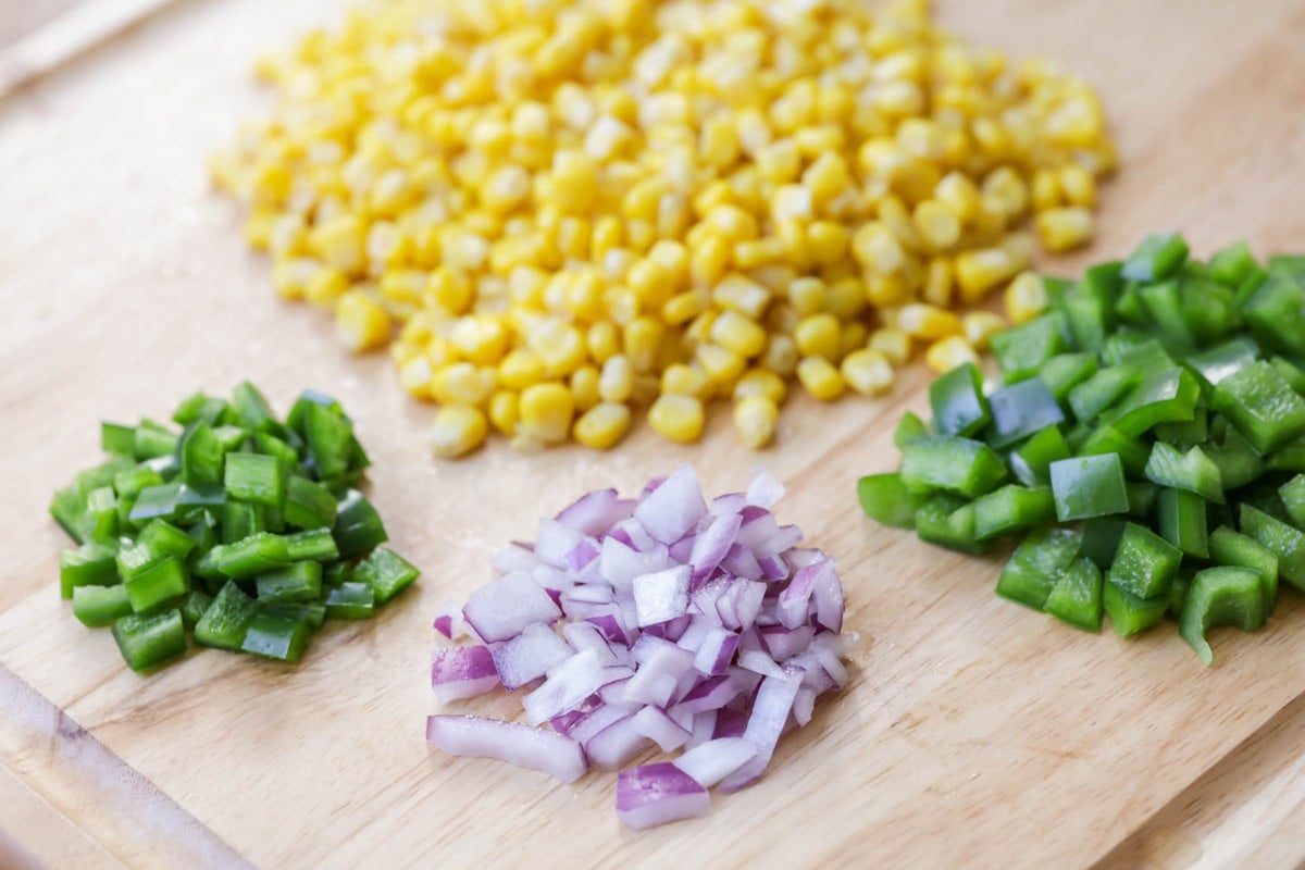 Corn, peppers, onions ingredients on a cutting board.