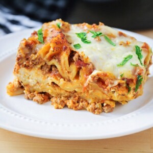 Crockpot lasagna sliced and served on a white plate.