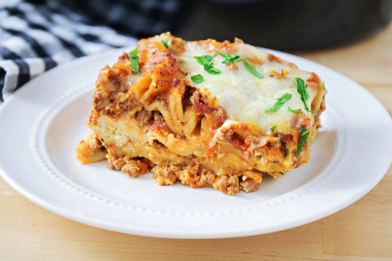 Crockpot lasagna sliced and served on a white plate.