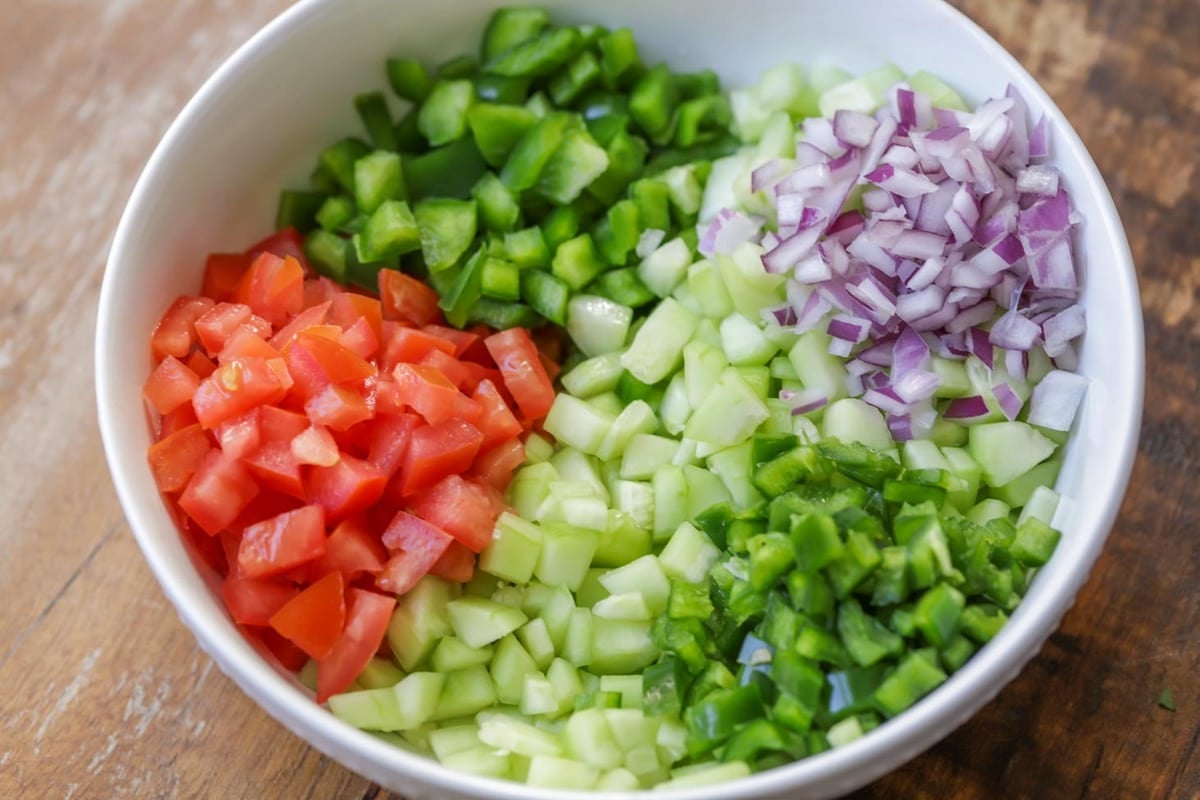 Ingredients for tomato cucumber salsa in a bowl.