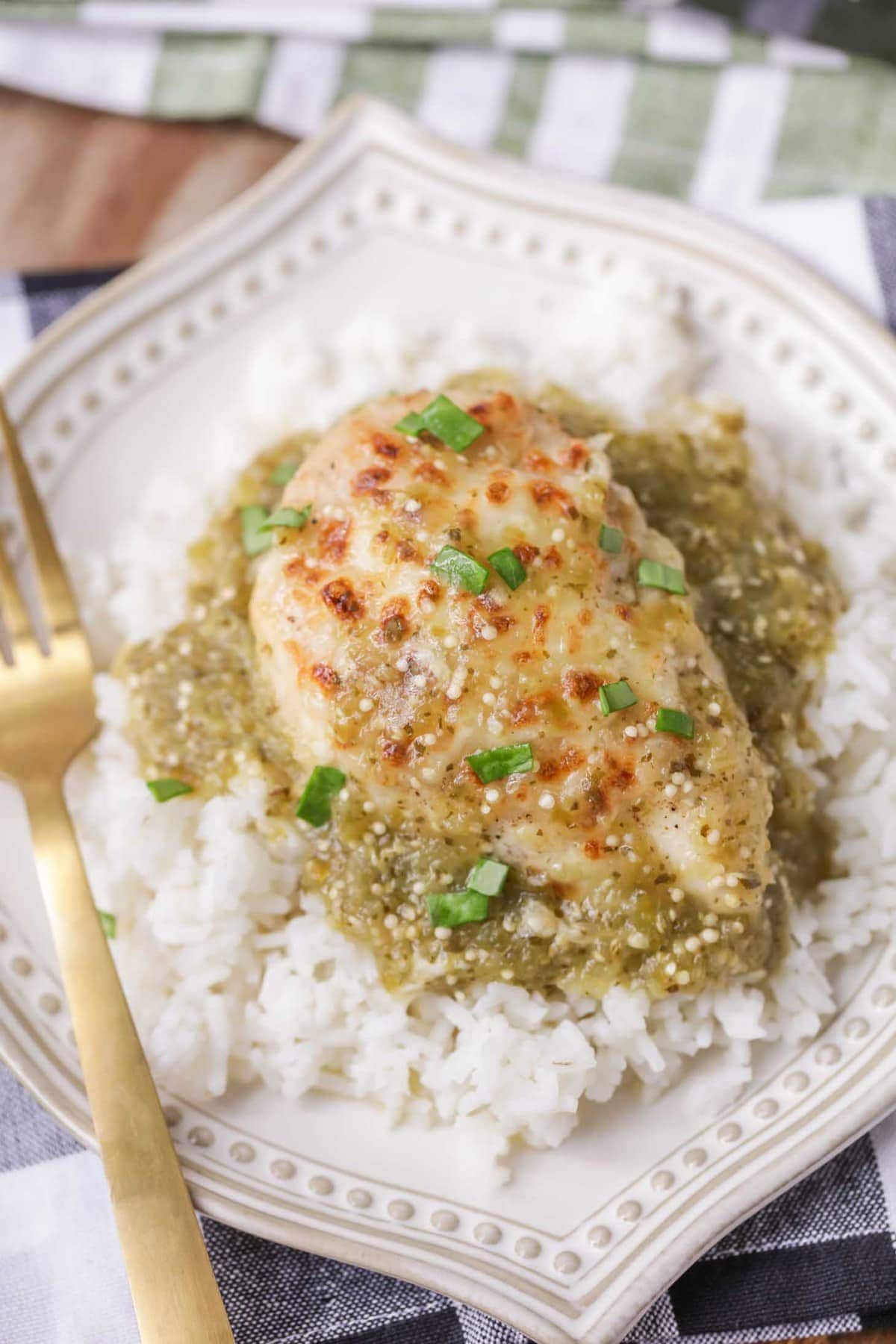 Salsa verde chicken served over rice on plate,