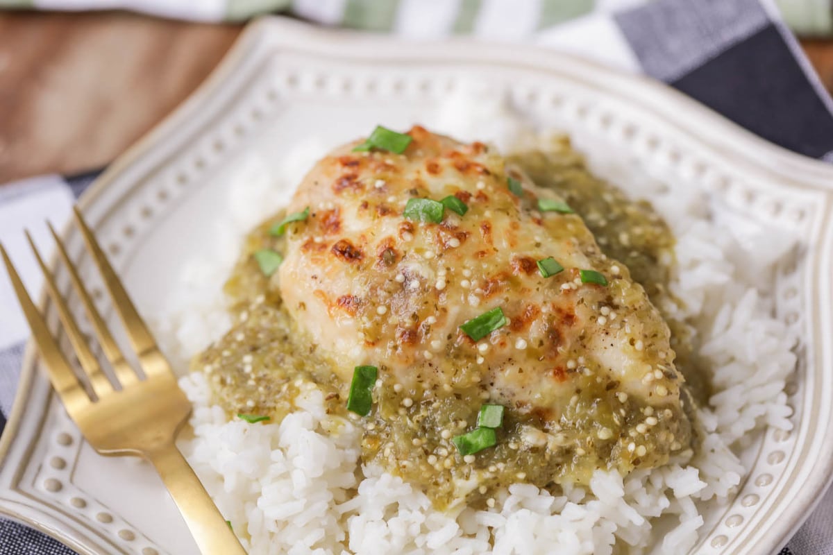 Salsa verde chicken served over rice on plate.