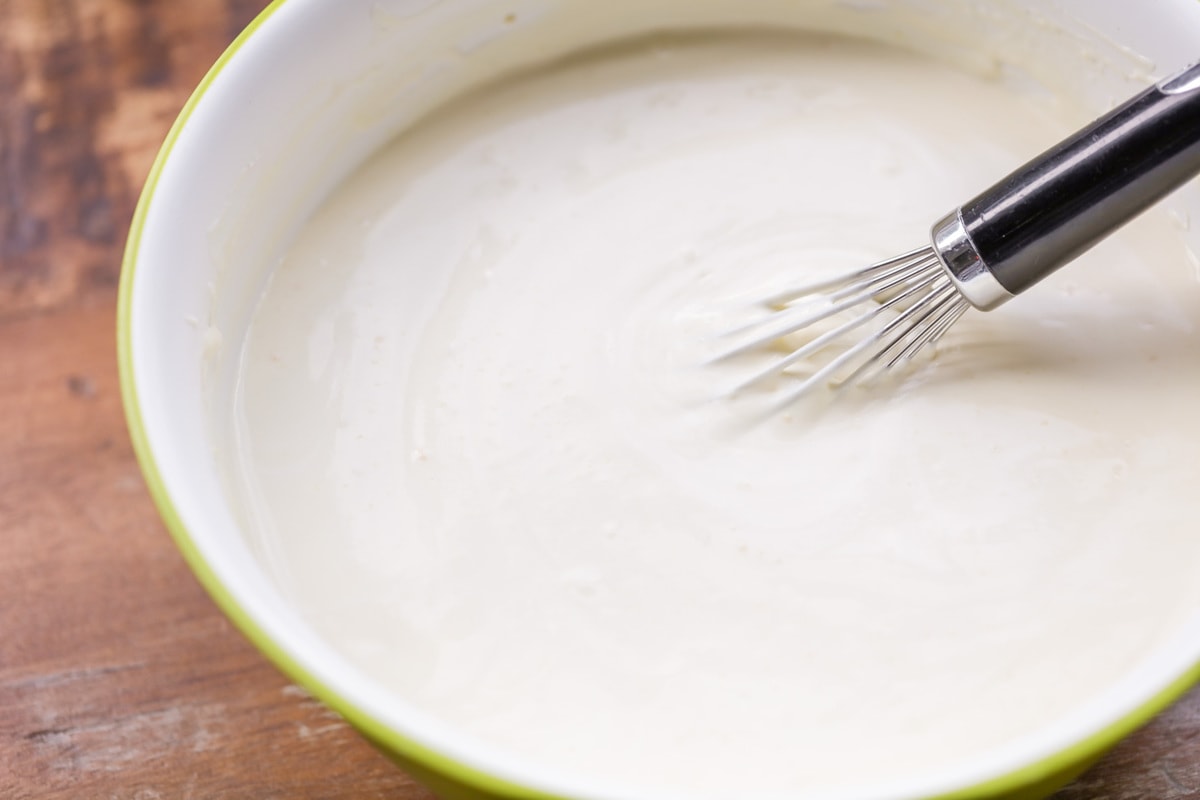 Homemade Banana Pudding being mixed in a  yellow bowl.