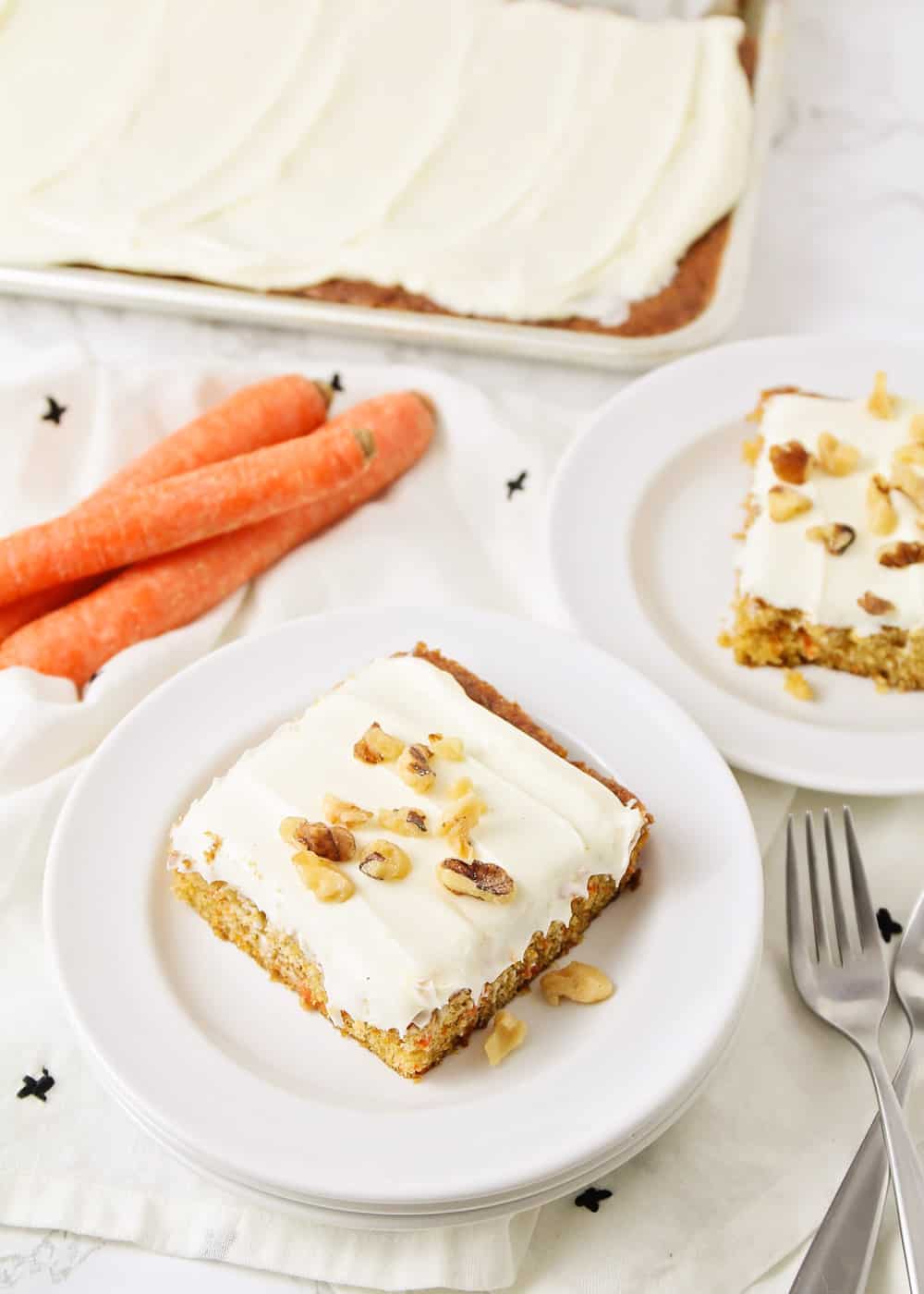 Easy Carrot cake recipe slice on a plate topped with cream cheese frosting and walnuts.