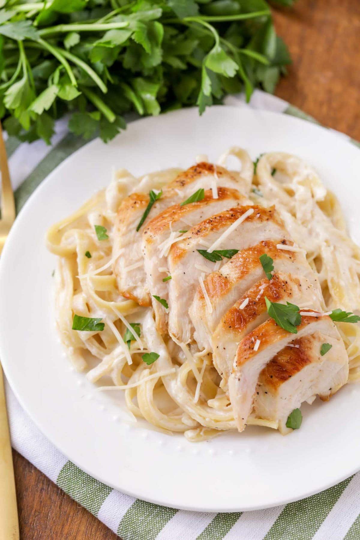 Chicken Alfredo served with fresh parsley on a white plate.