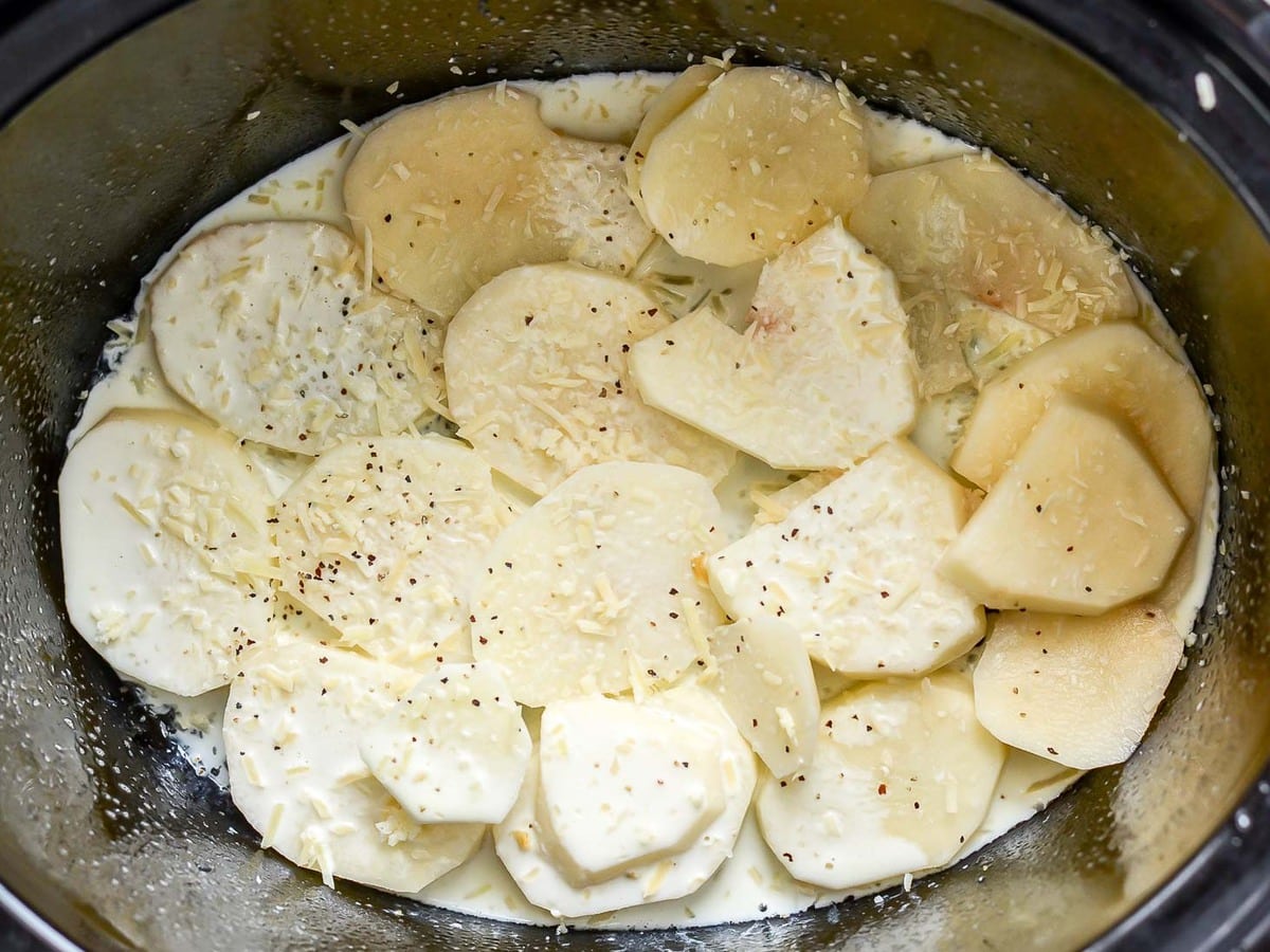 Prepping ingredients for crock pot scalloped potatoes in a slow cooker.