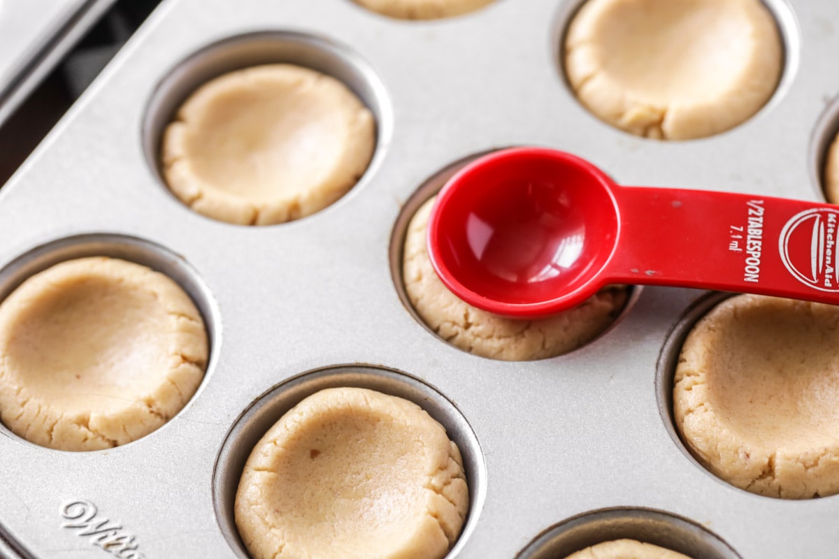 Using a teaspoon to make indents in Peanut Butter Cup Cookies before baking