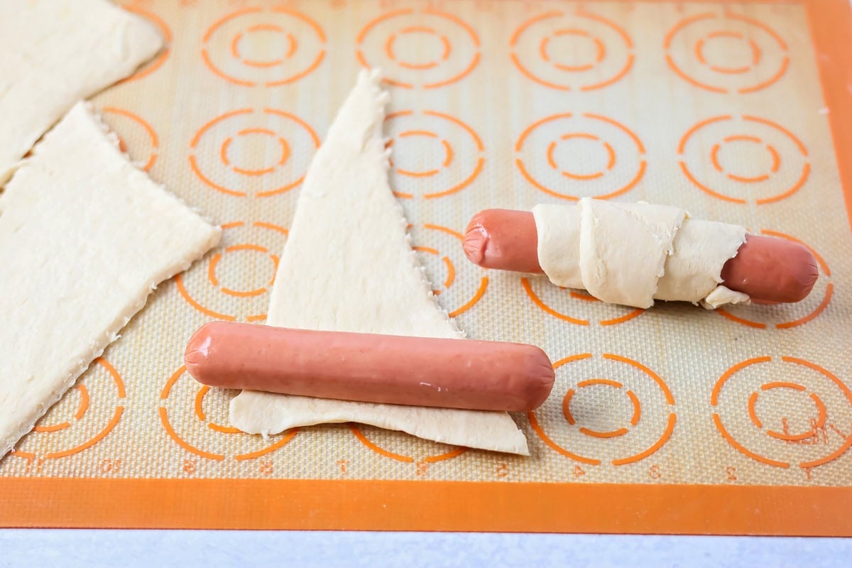 Wrapping hot dogs in crescent dough on Silpat.