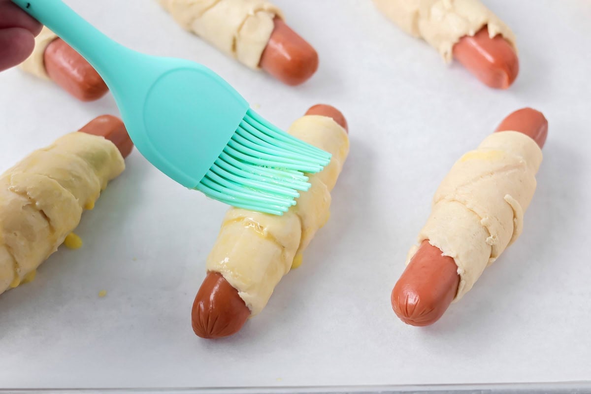 Brushing on egg wash for homemade Pigs in a Blanket recipe.