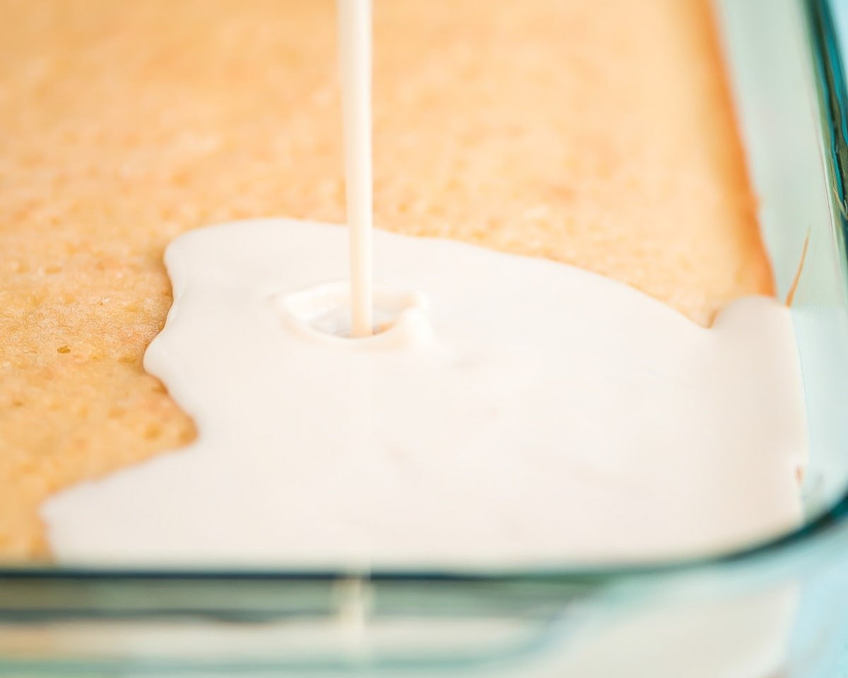How to Make Tres Leches Cake by pouring milk mixture over the cake
