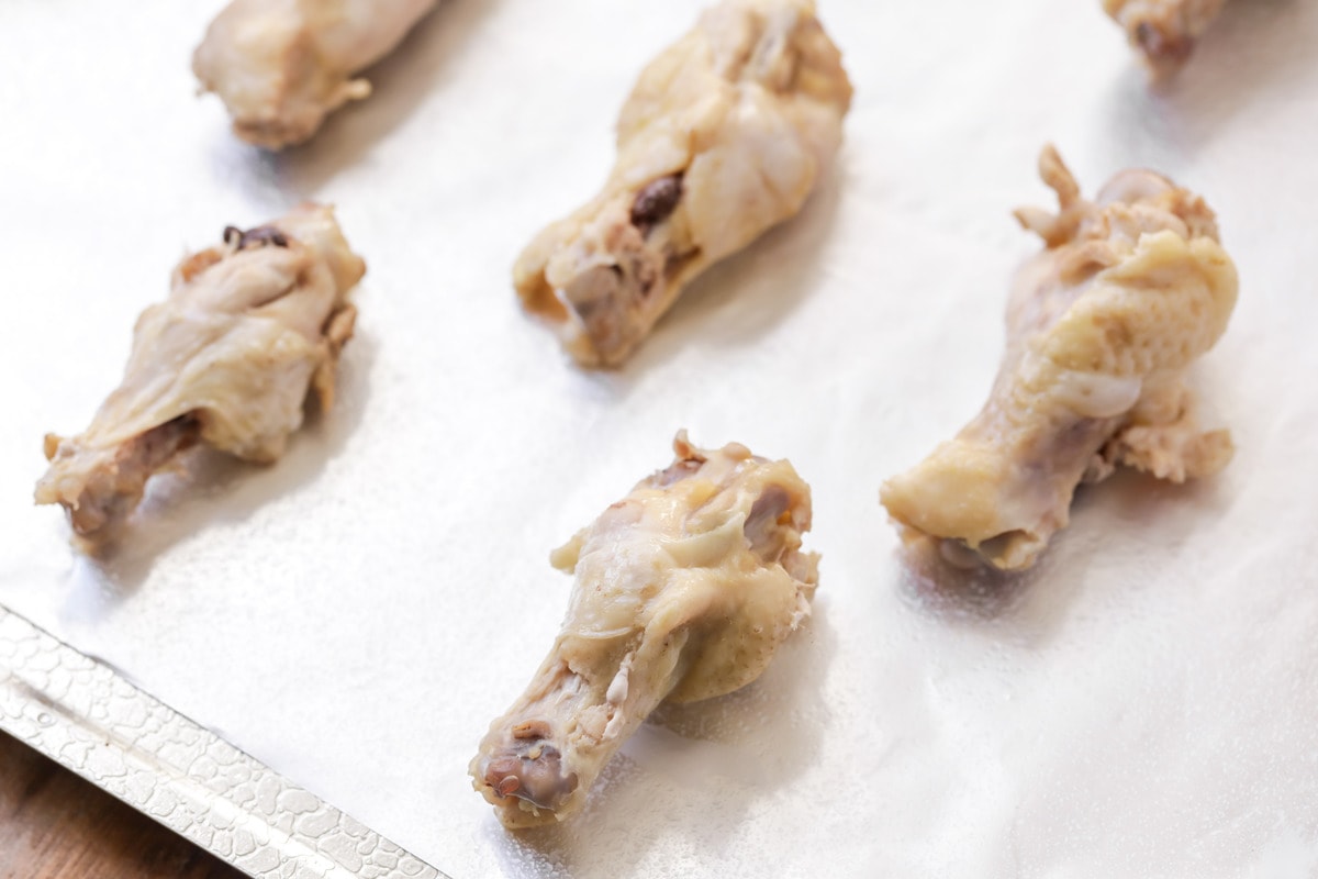 raw chicken wings on a baking sheet with parchment paper for baked chicken wings