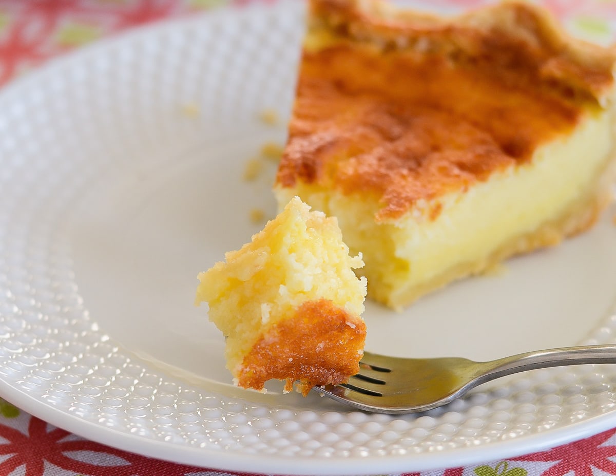 Buttermilk pie slice with a fork full on a white plate.