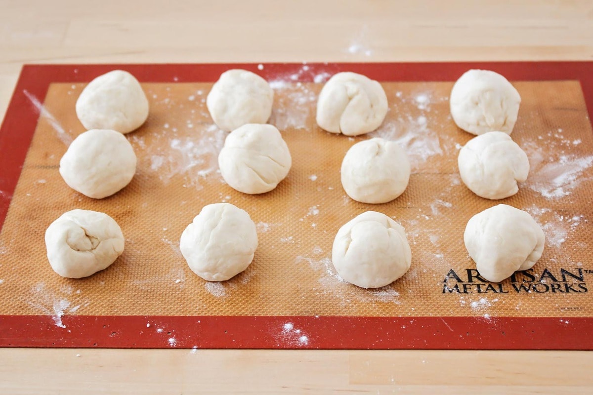 Flour tortilla dough balls rolled on a mat.