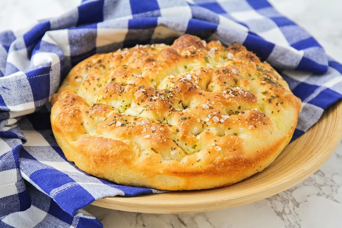 Fresh focaccia served on a blue gingham cloth.