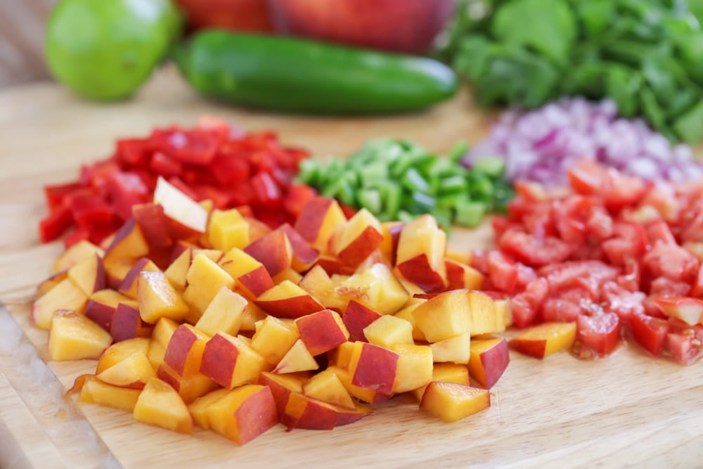 Peaches and veggies cut on a board.