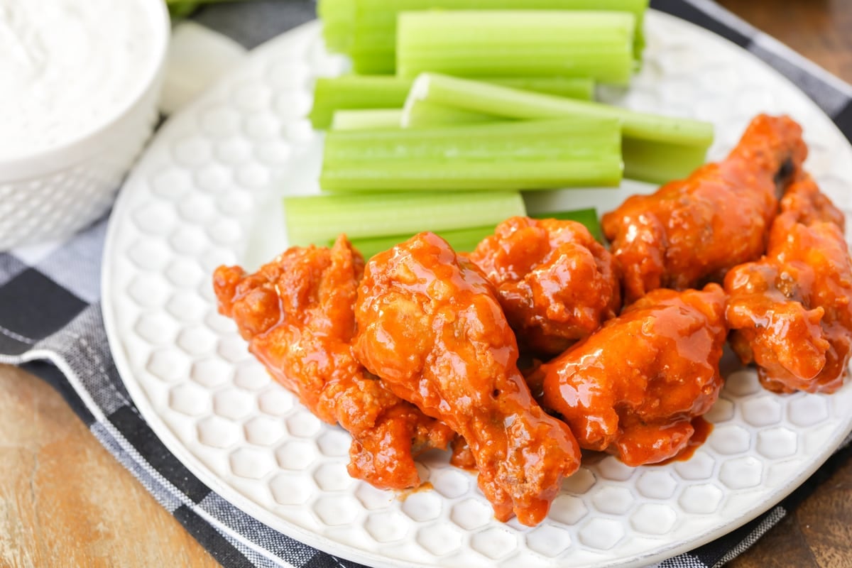 Buffalo wings served on a plate with celery.