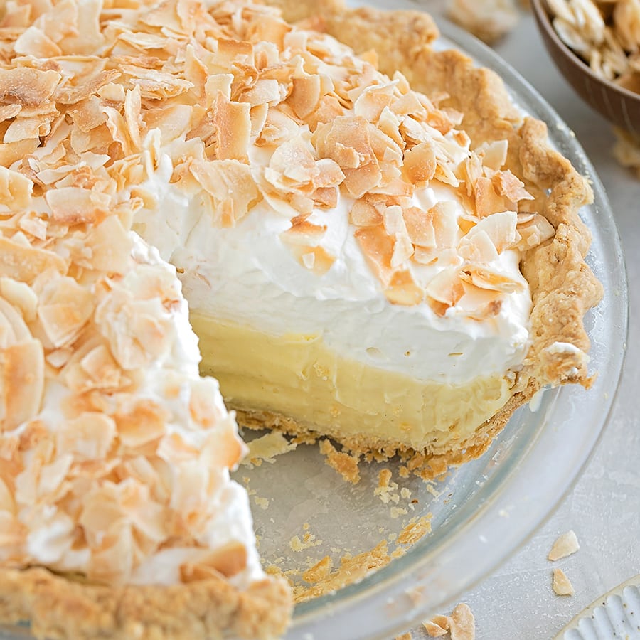 Coconut cream pie in a pie pan with a missing slice.