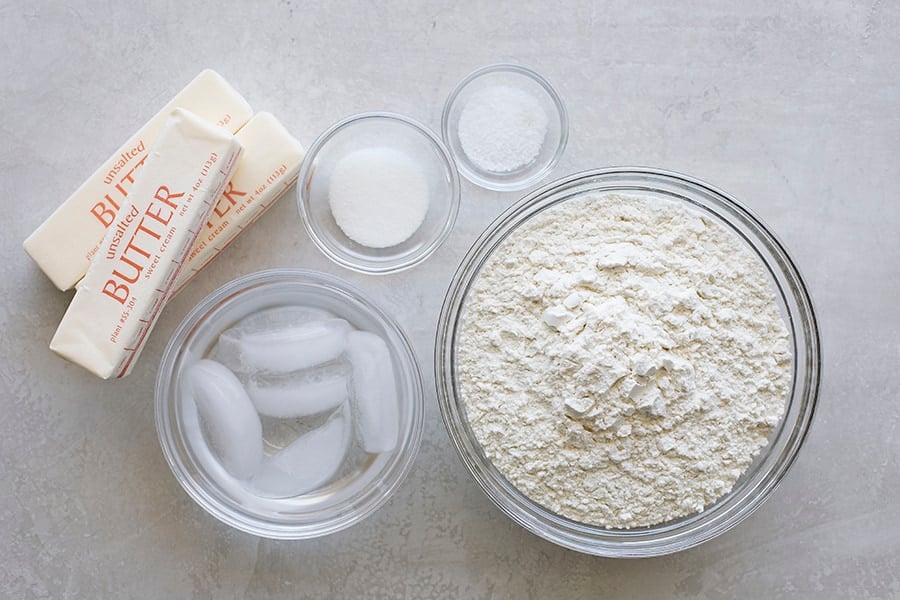 Measured flour, sugar, salt, and butter on a kitchen counter.