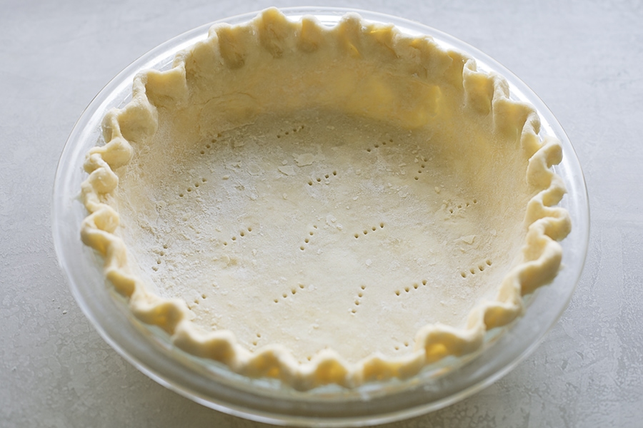 A pie crust in a glass pie dish.