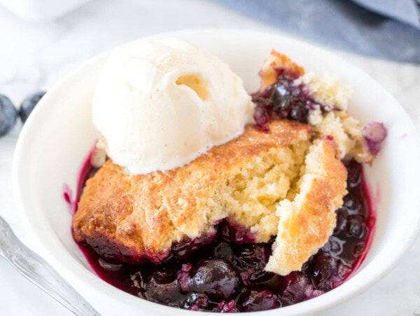 Delicious blueberry cobbler with a fluffy biscuit top and tons of juice blueberries served with a scoop of vanilla ice cream.