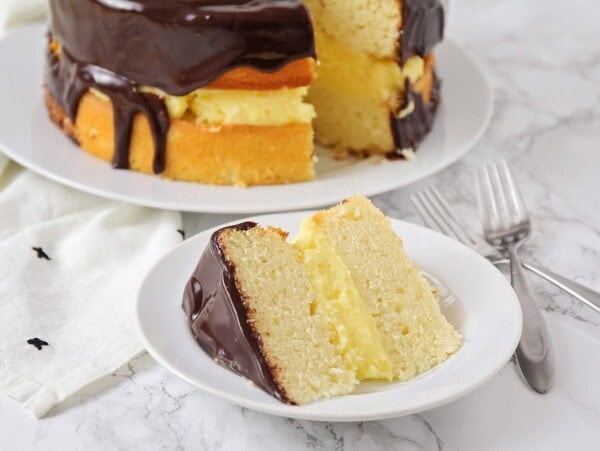 A slice of boston cream pie served on a white plate.