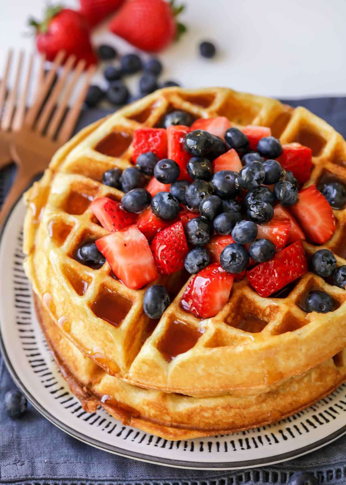 Homemade buttermilk waffle topped with berries and syrup.