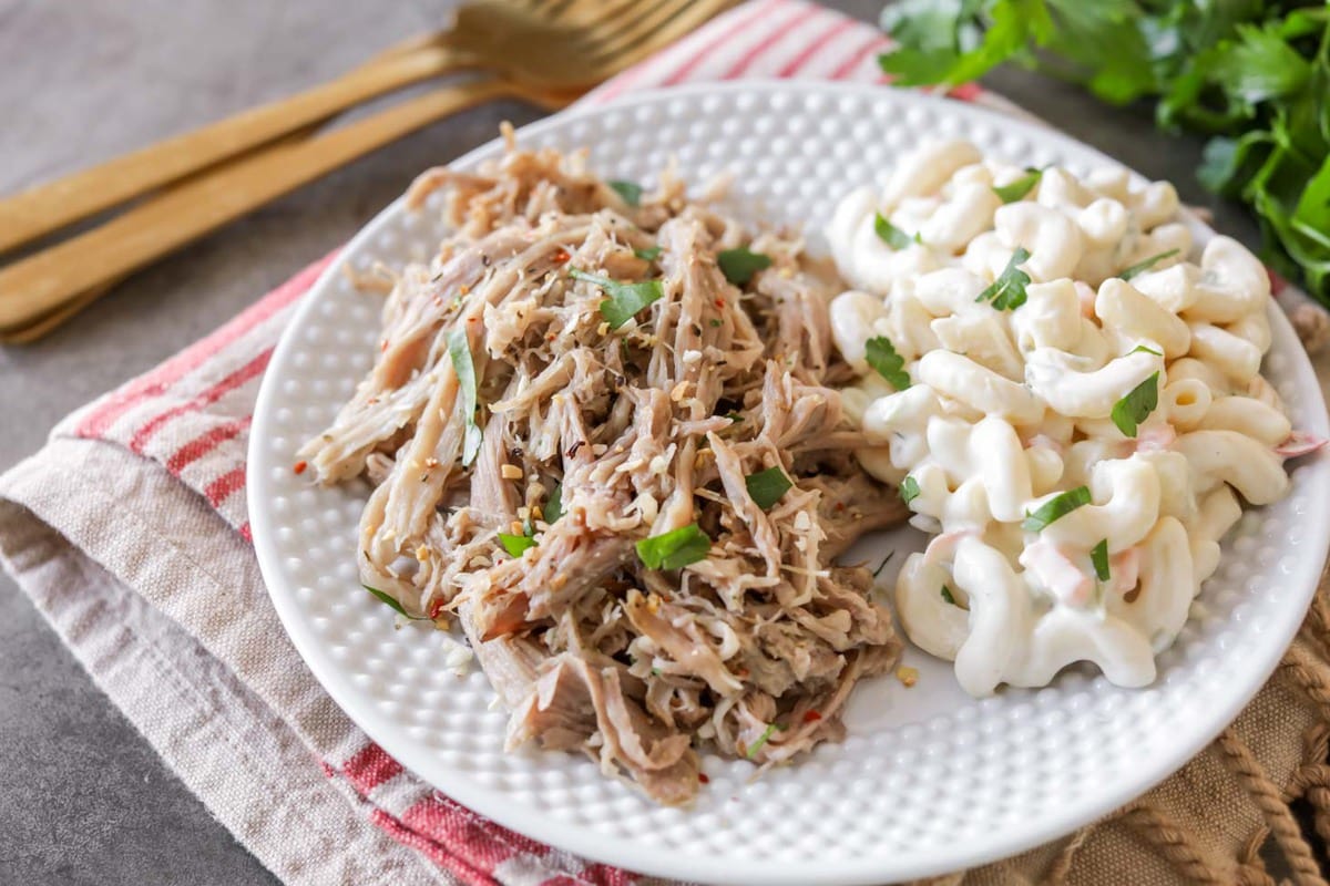 Summer Crockpot Recipes - Slow cooker kalua pork served on a white plate with macaroni salad.