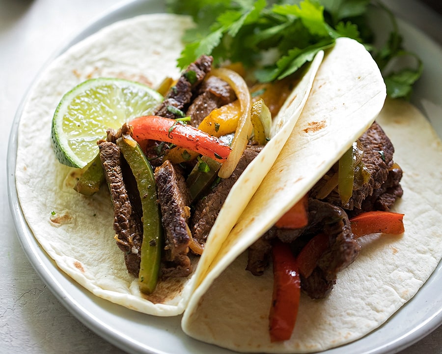 Steak fajitas with a lime wedge and cilantro