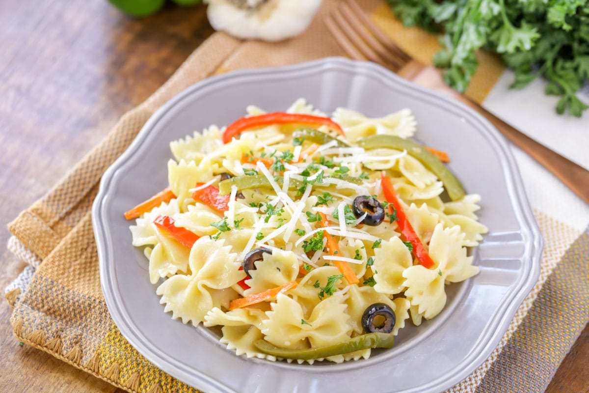 Primavera pasta on a grey plate topped with parsley.