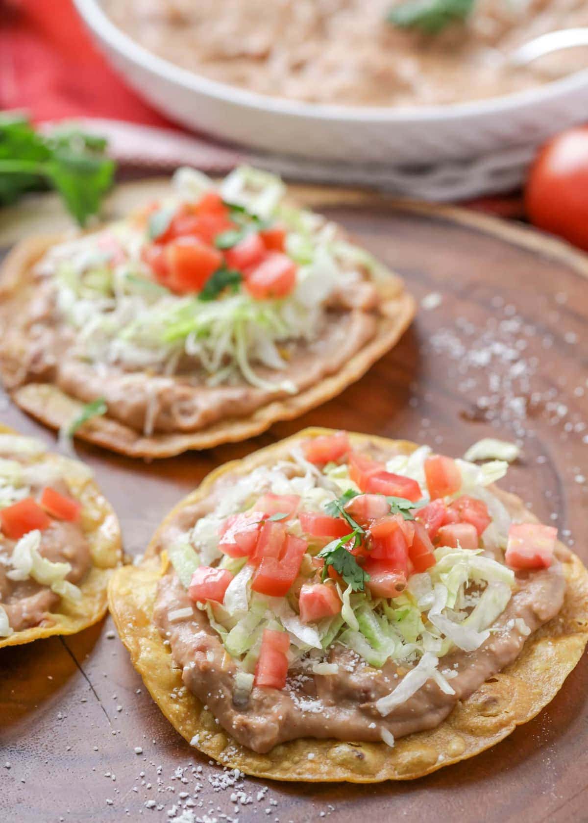 Three bean tostadas with various toppings on a platter.