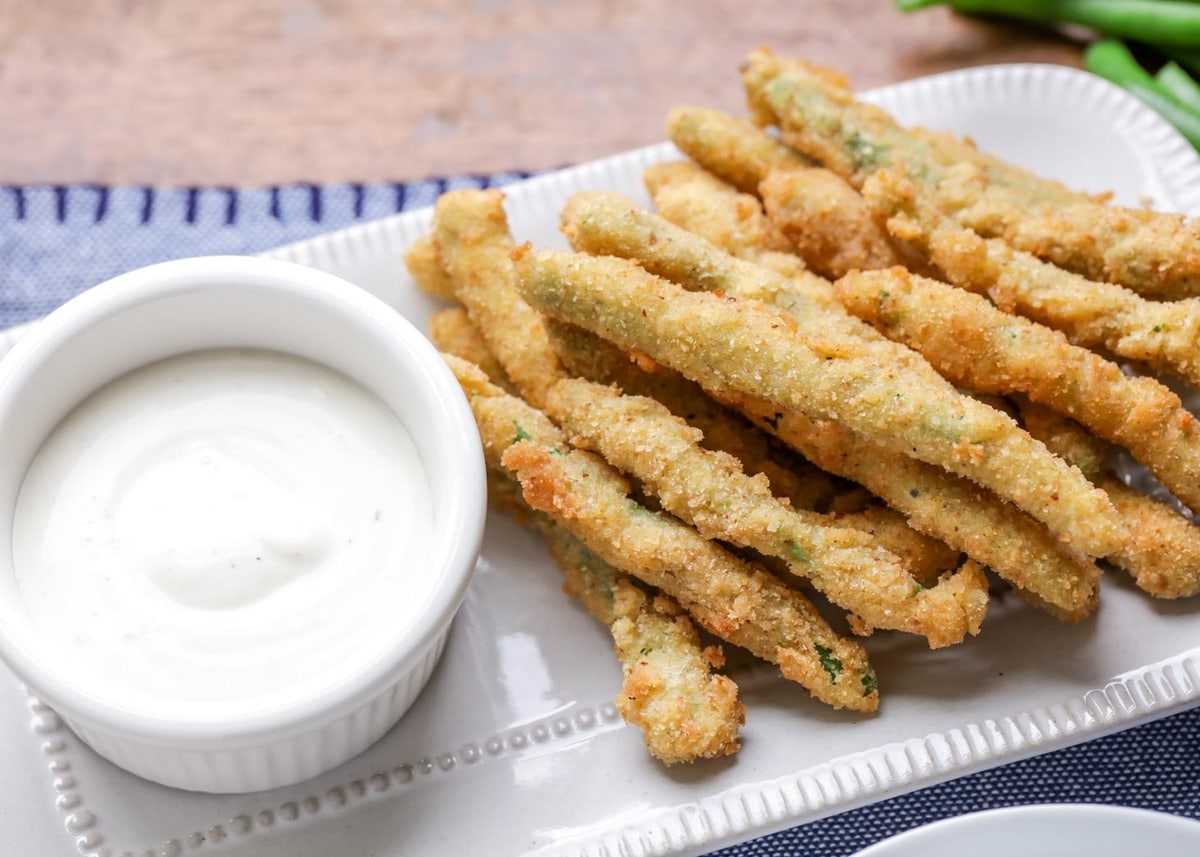 Fried green Beans on a platter with ranch dipping sauce.