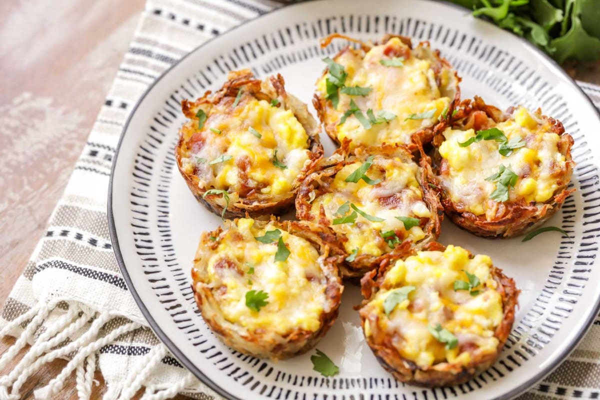 Christmas breakfast ideas - 6 hash brown egg cups plated and topped with fresh herbs.