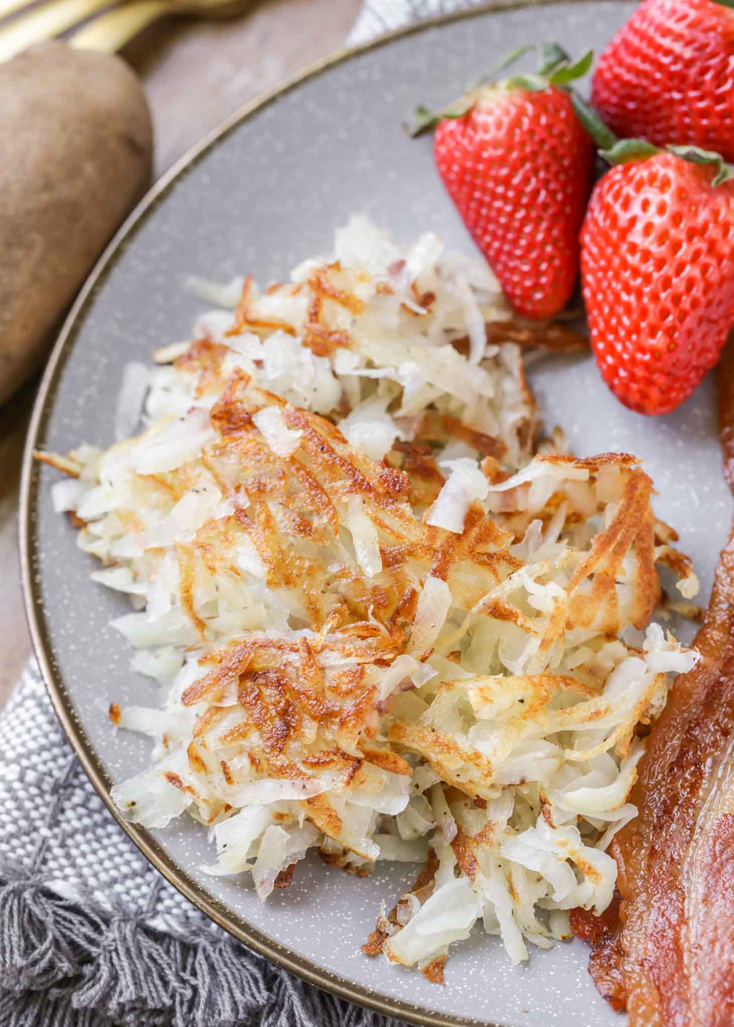 homemade hash browns on a plate with bacon and strawberries