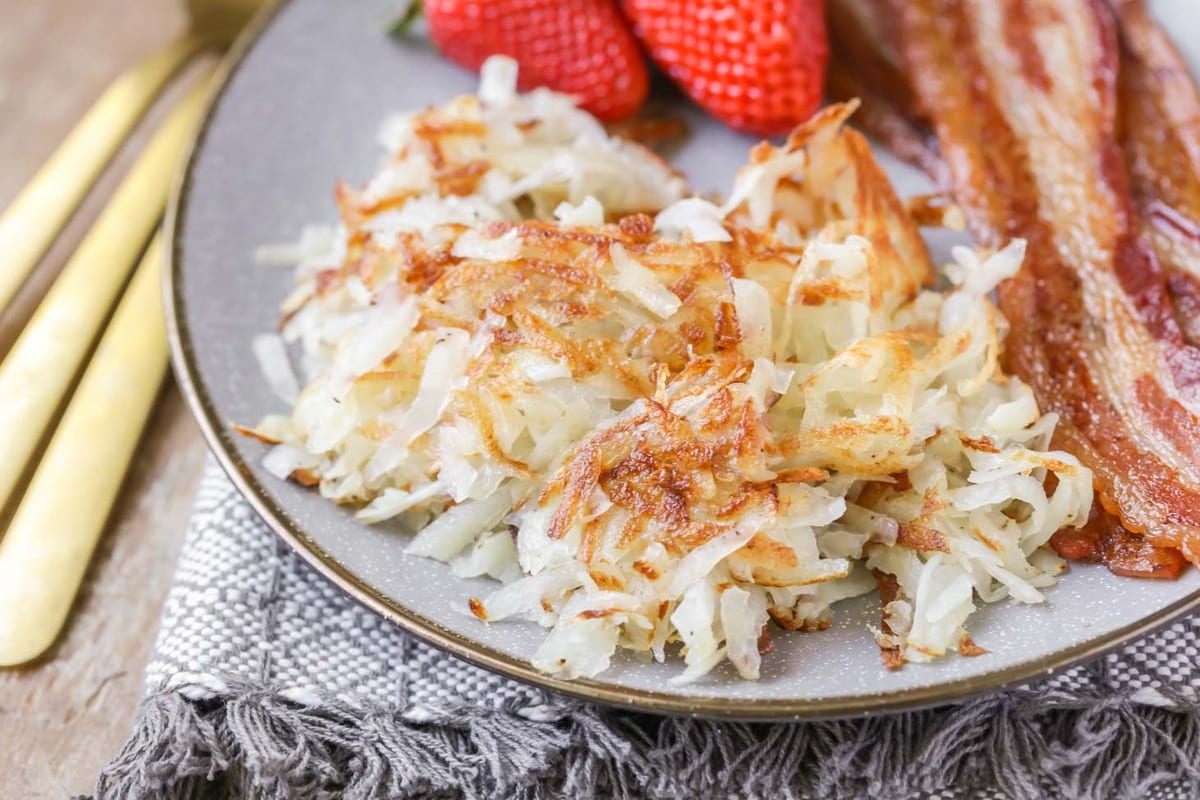 Easy Breakfast Ideas - hash browns with  sides of bacon and whole strawberries on a gray plate. 
