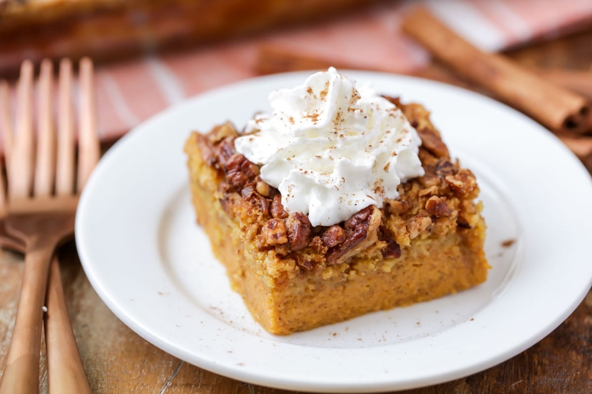 Pumpkin Crunch Cake topped with whipped cream served on a white plate.