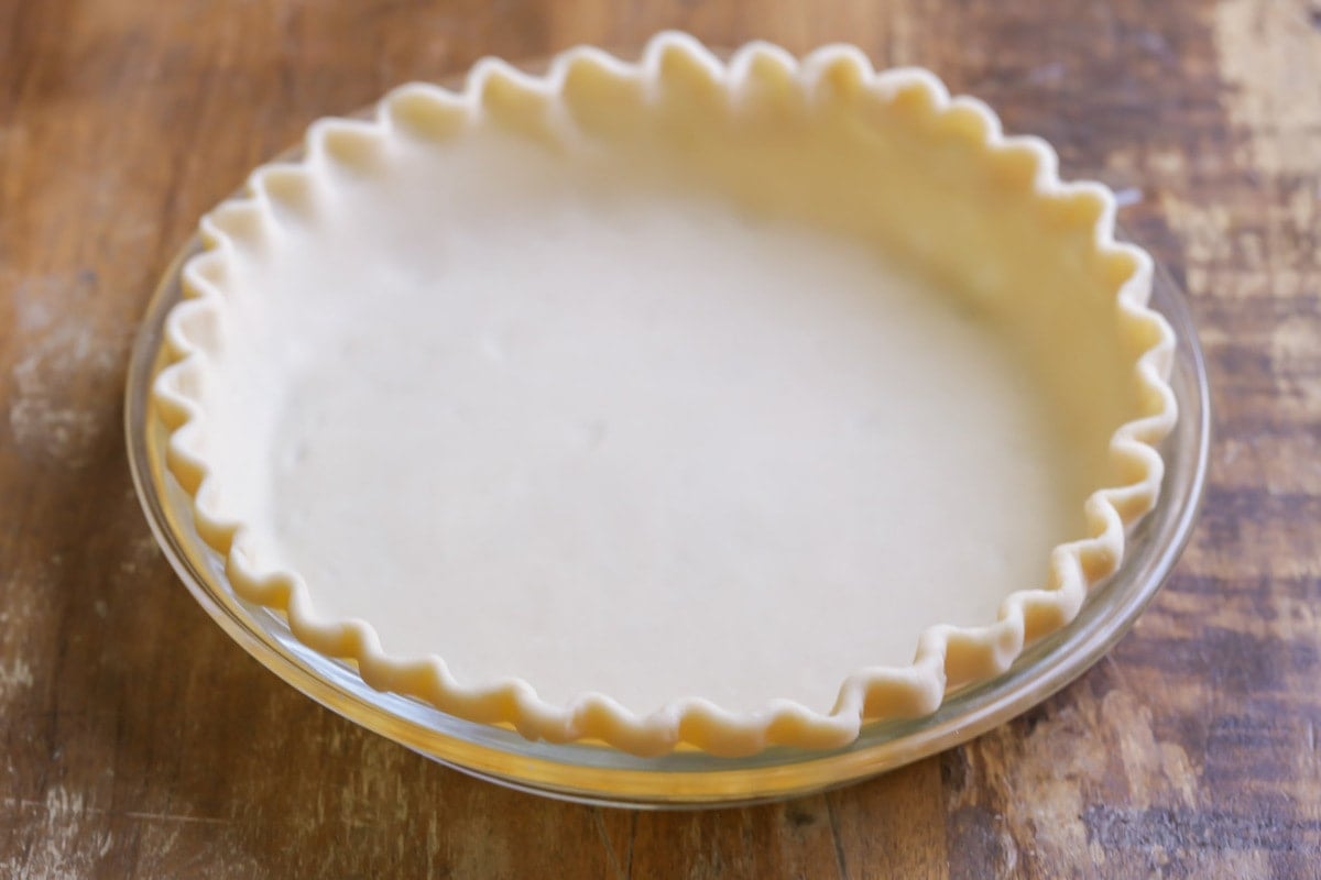 Pie crust in a dish for bacon and cheese quiche recipe.
