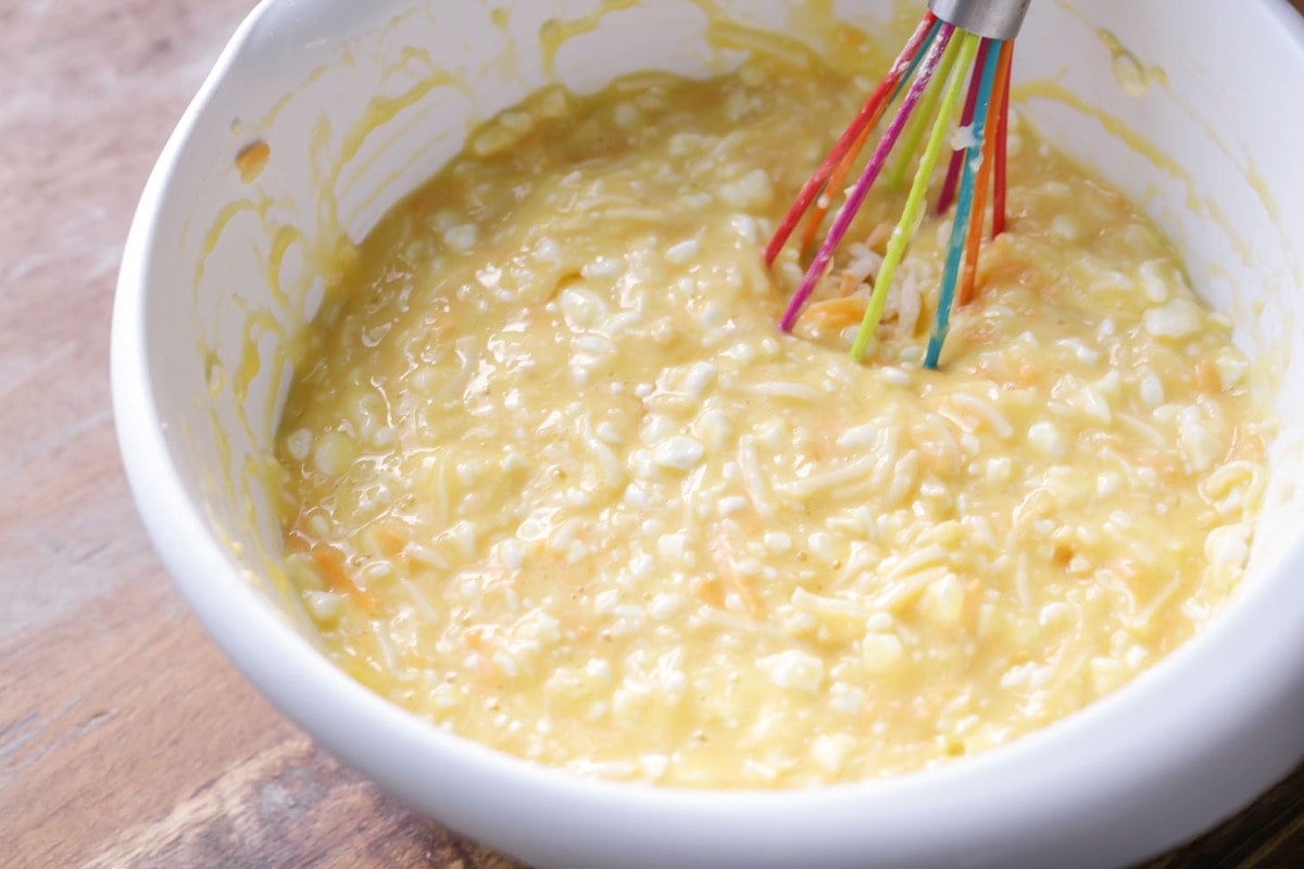 Egg, cheese and cottage cheese mixture in a white bowl for making baked eggs.