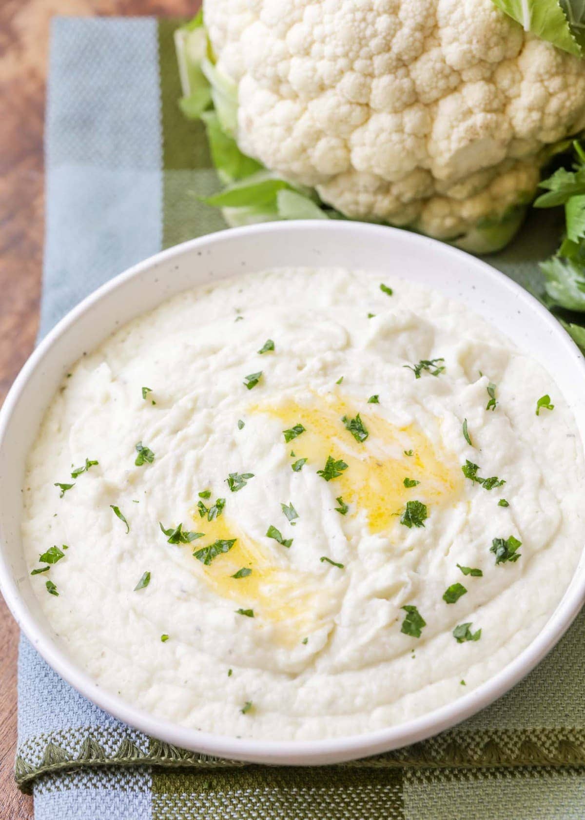 garlic mashed cauliflower topped with parsley in a white bowl 