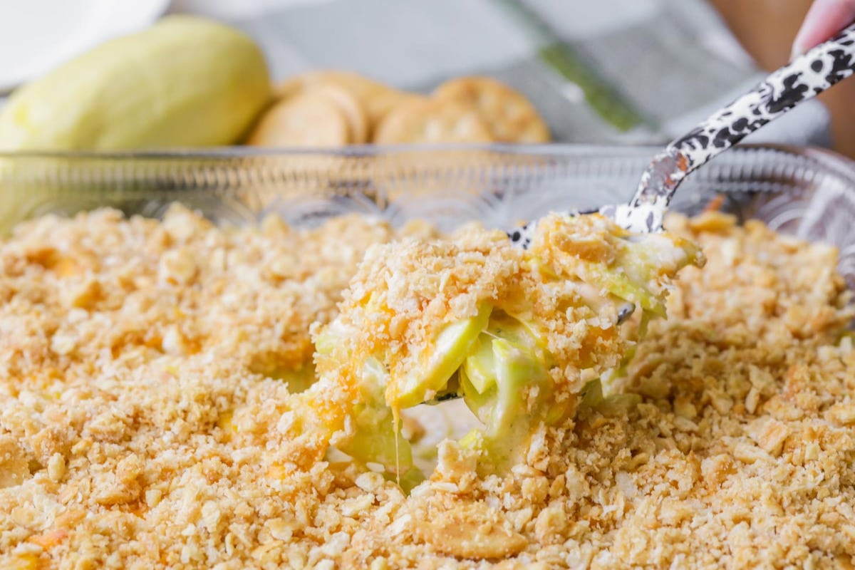 Yellow squash casserole being scooped with a serving spoon.