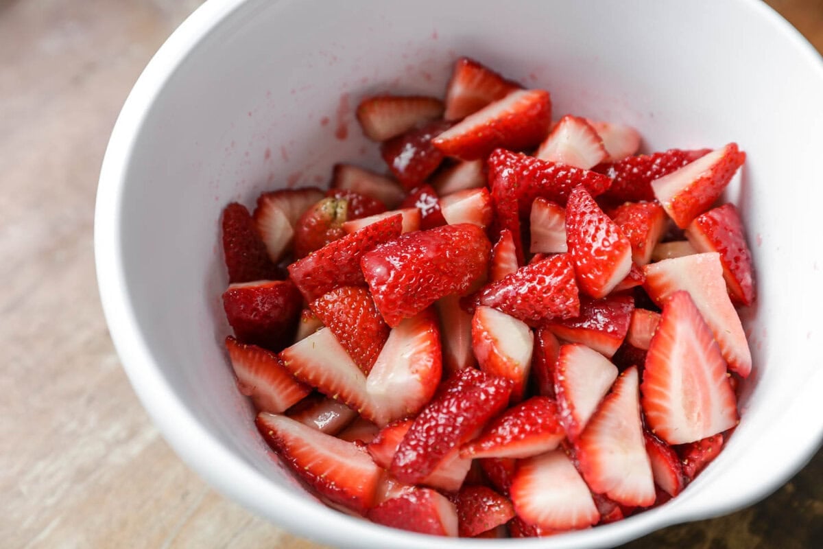 Sliced strawberries in a white bowl.