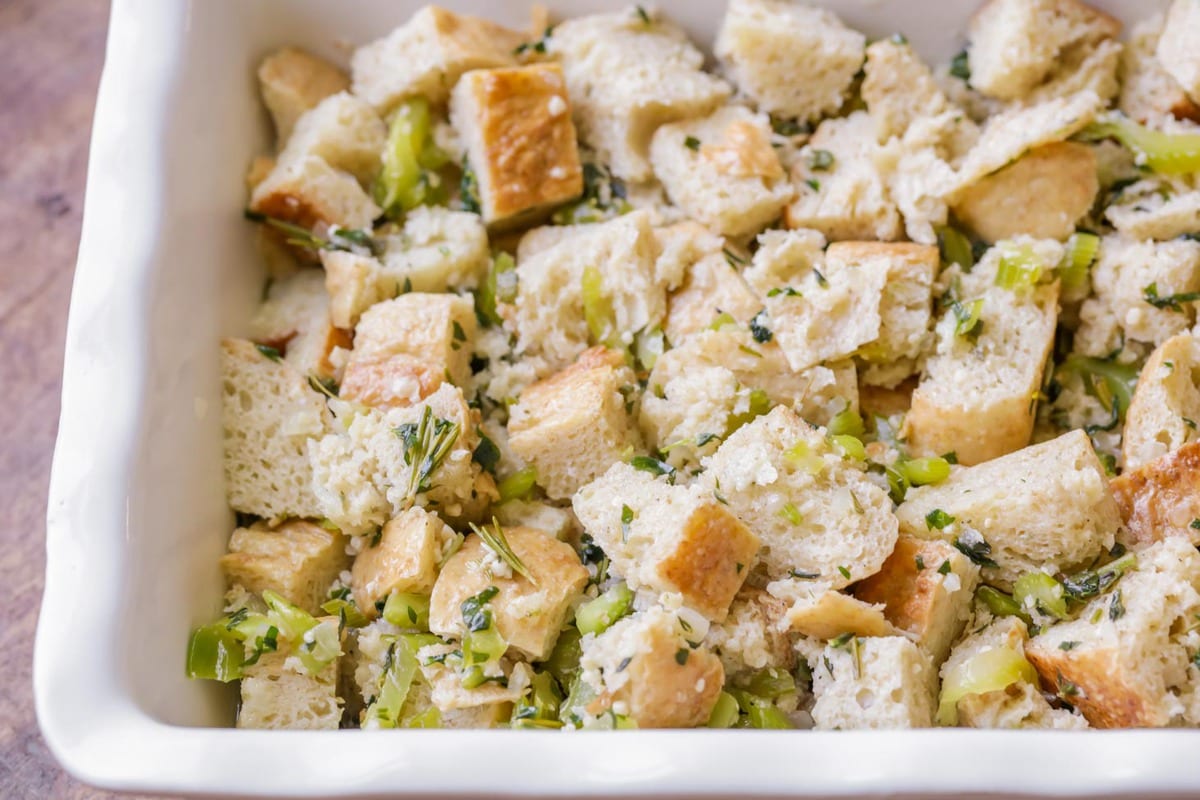 Bread stuffing recipe with celery and seasonings in a white dish.