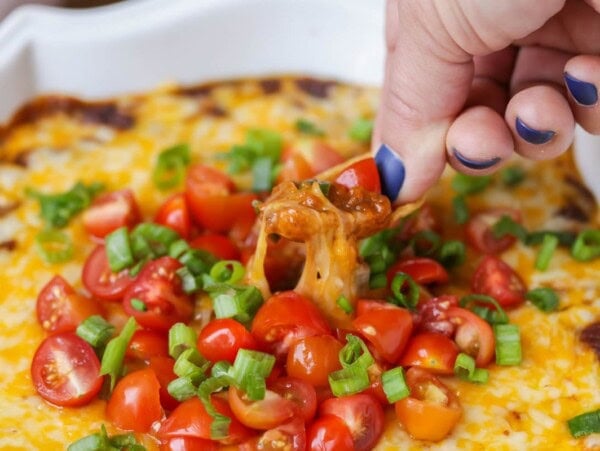 Scooping chili cheese dip from a baking dish.