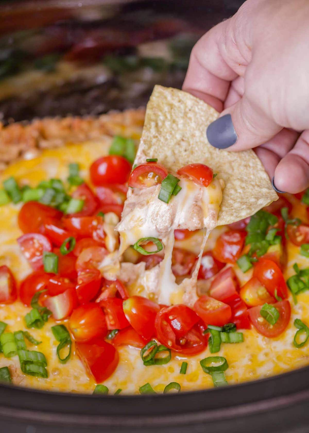 close up of crock pot bean dip topped with tomatoes
