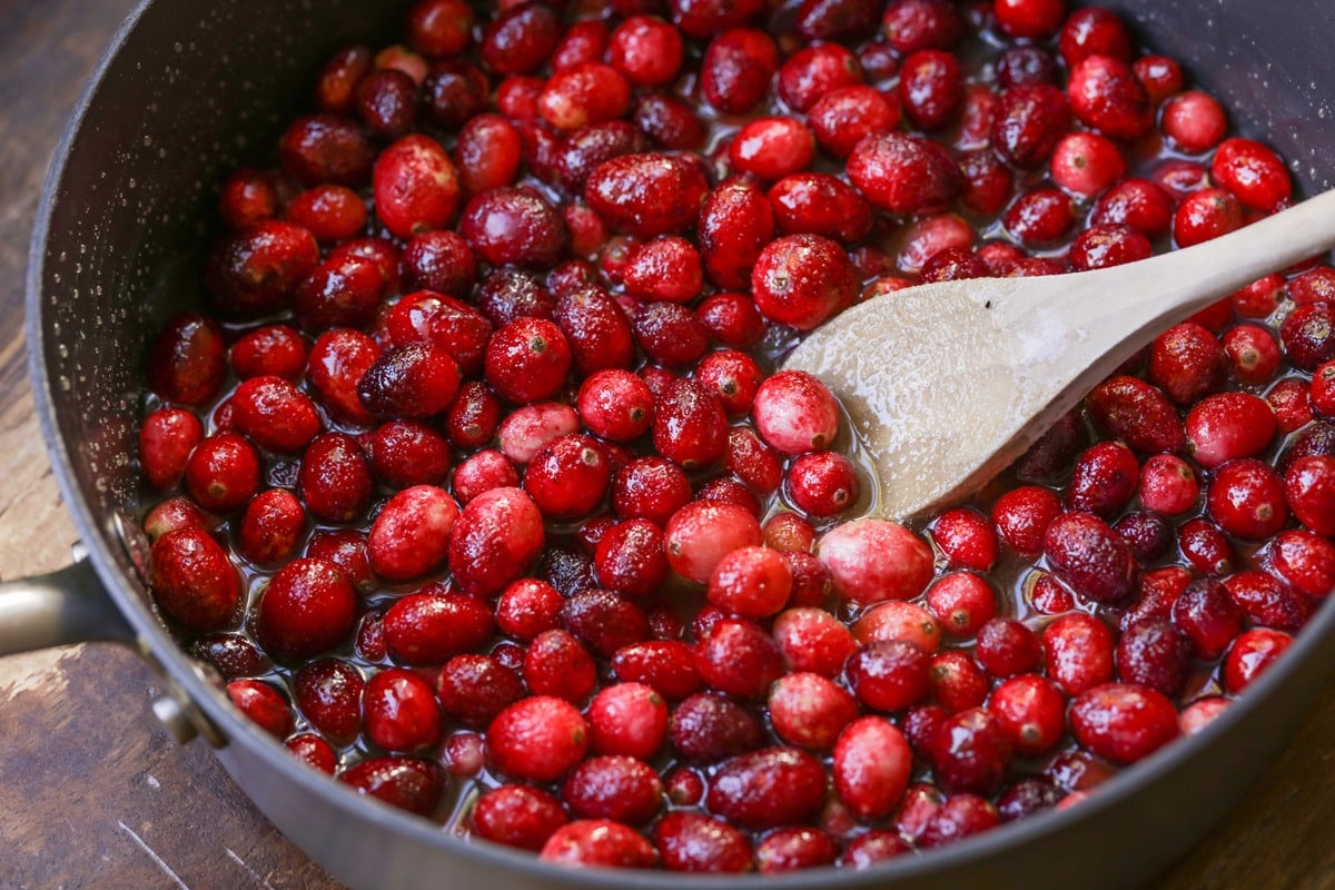 Cranberries being cooked in a saucepan for fresh cranberry sauce.