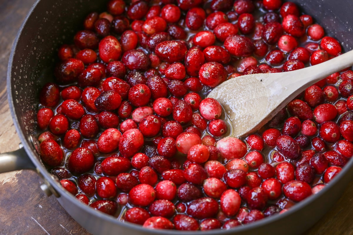 Cranberries being cooked in a saucepan.