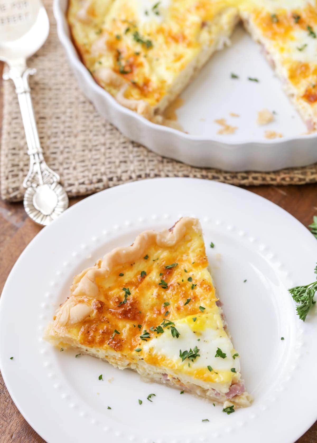 Ham and cheese quiche slice served on a white plate.