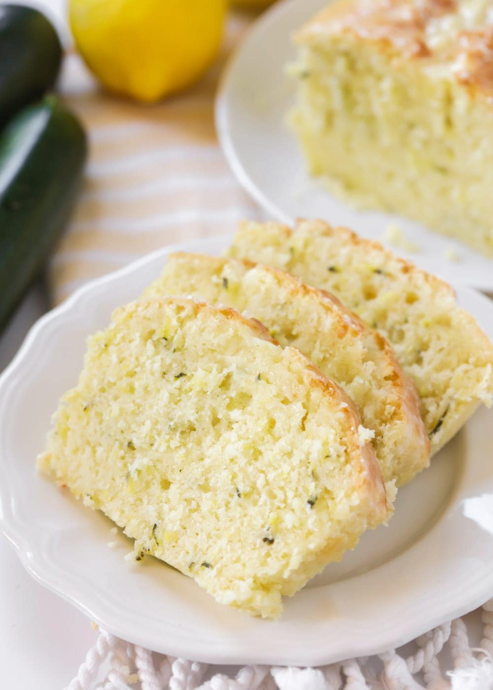 Three slices of lemon zucchini bread recipe on a white plate.